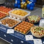 Delicious graduation party food spread with sliders, chips, and salads for large gatherings.