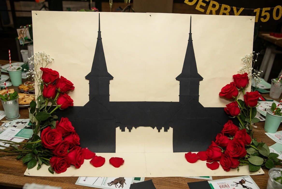 Decorative silhouette of Churchill Downs with red roses.