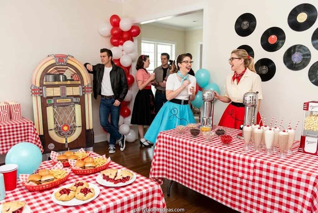 Retro 1950s diner party with checkerboard tablecloths, jukebox decor, milkshake bar, cherry red accents, and vintage soda shop vibes.