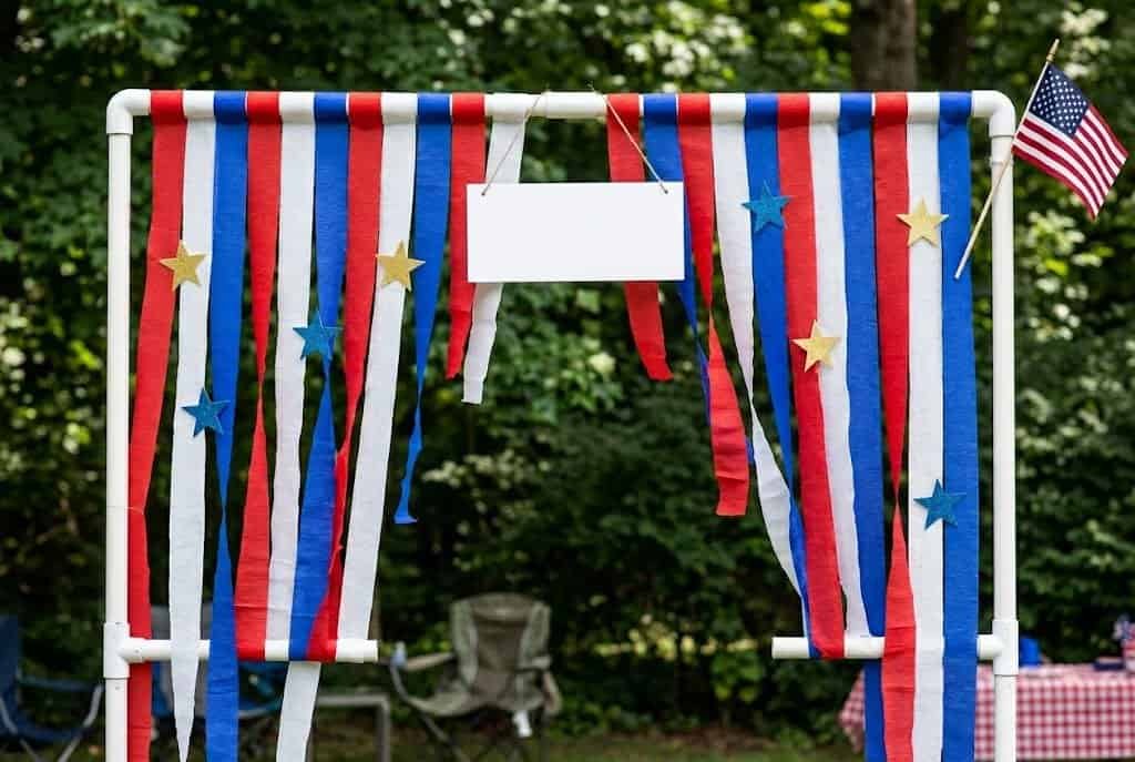 Patriotic 4th of July outdoor party backdrop with red, white, and blue streamers and stars