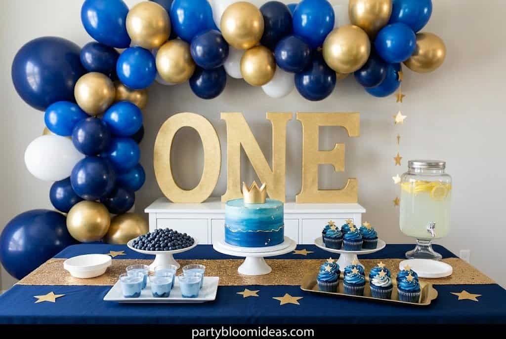 Blue, gold, and white balloon arch with "ONE" sign for first birthday celebration.