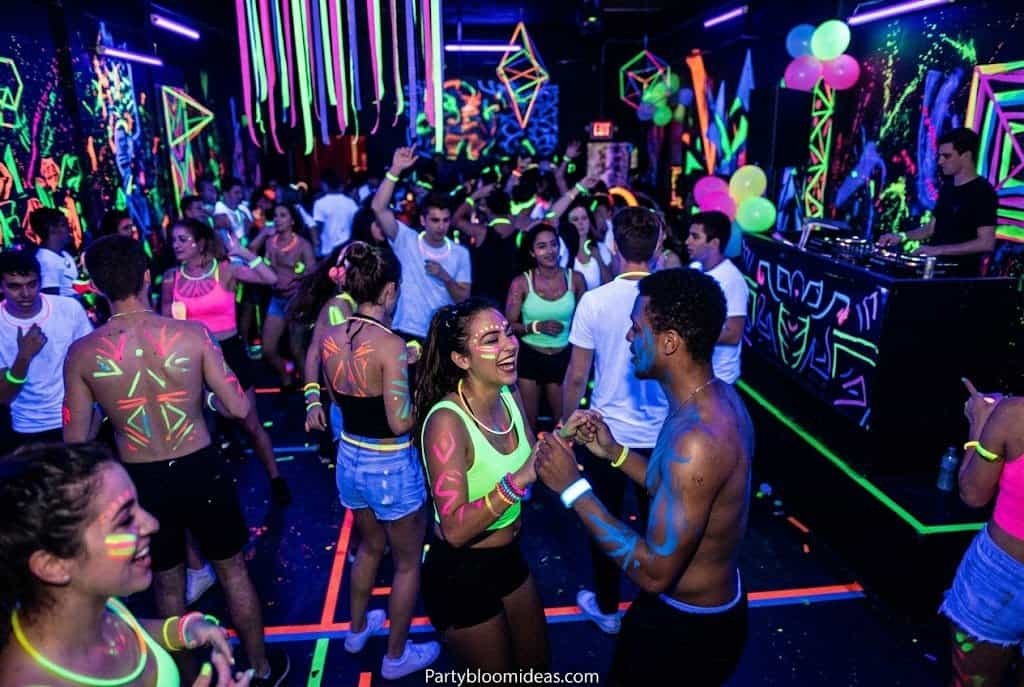 Neon UV glow disco party setup with blacklights, glowing flowers, and colorful cups.