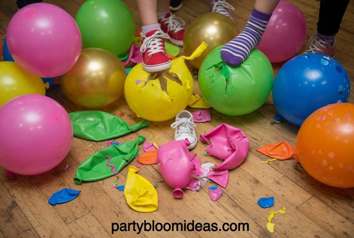 Players trying to pop balloons tied to ankles during a chaotic outdoor party game