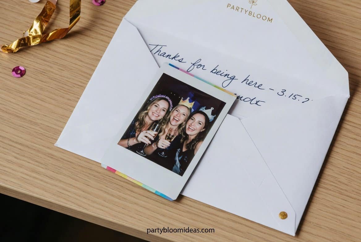 Instax mini photos inside personalized envelopes with handwritten thank-you notes displayed at a milestone birthday party exit table.