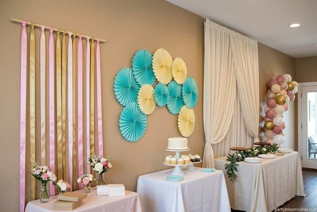 Dessert table backdrop with paper fans, fabric drape, and balloons for a party photo area