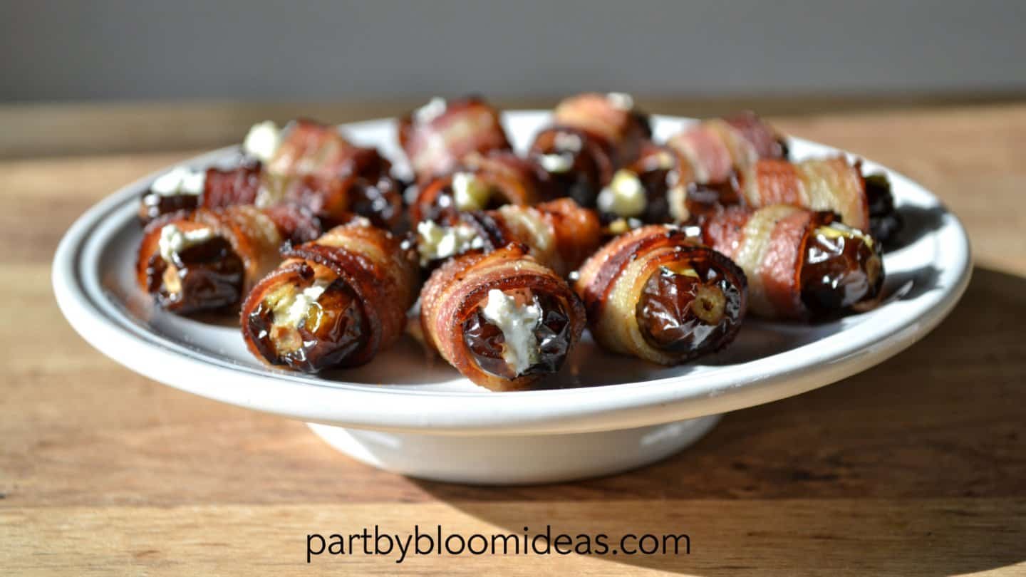 Bacon-wrapped dates stuffed with goat cheese on a white serving plate