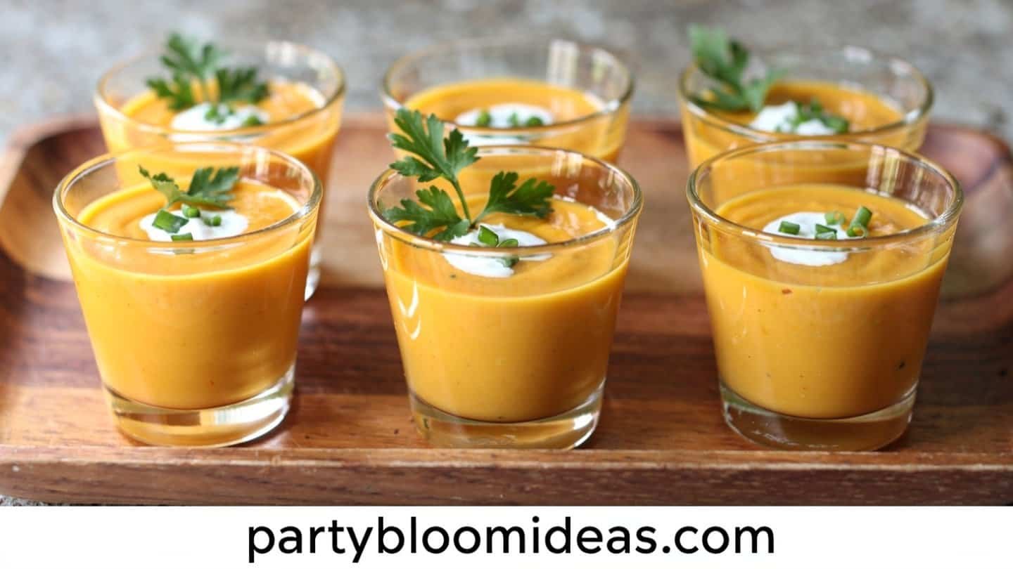 Butternut squash soup shooters in small glasses with a cream swirl and herb garnish