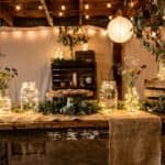 Rustic wedding table setup featuring lanterns, flowers, and greenery for a charming celebration.