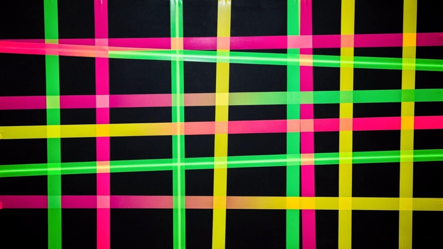 Bright neon pink, green, and yellow tape grid wall for glow party photos