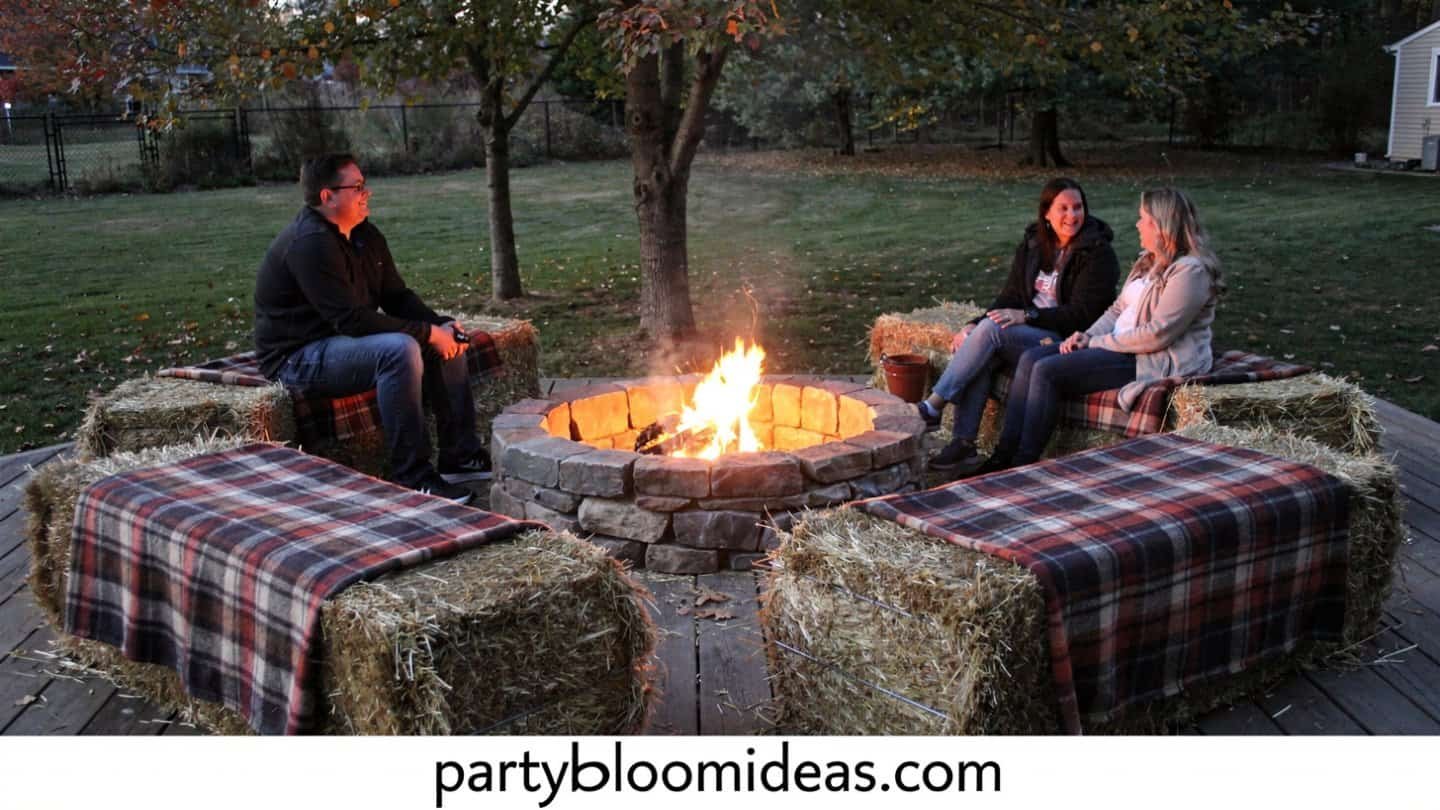 Outdoor fire pit with hay bale seating and plaid throws for guests