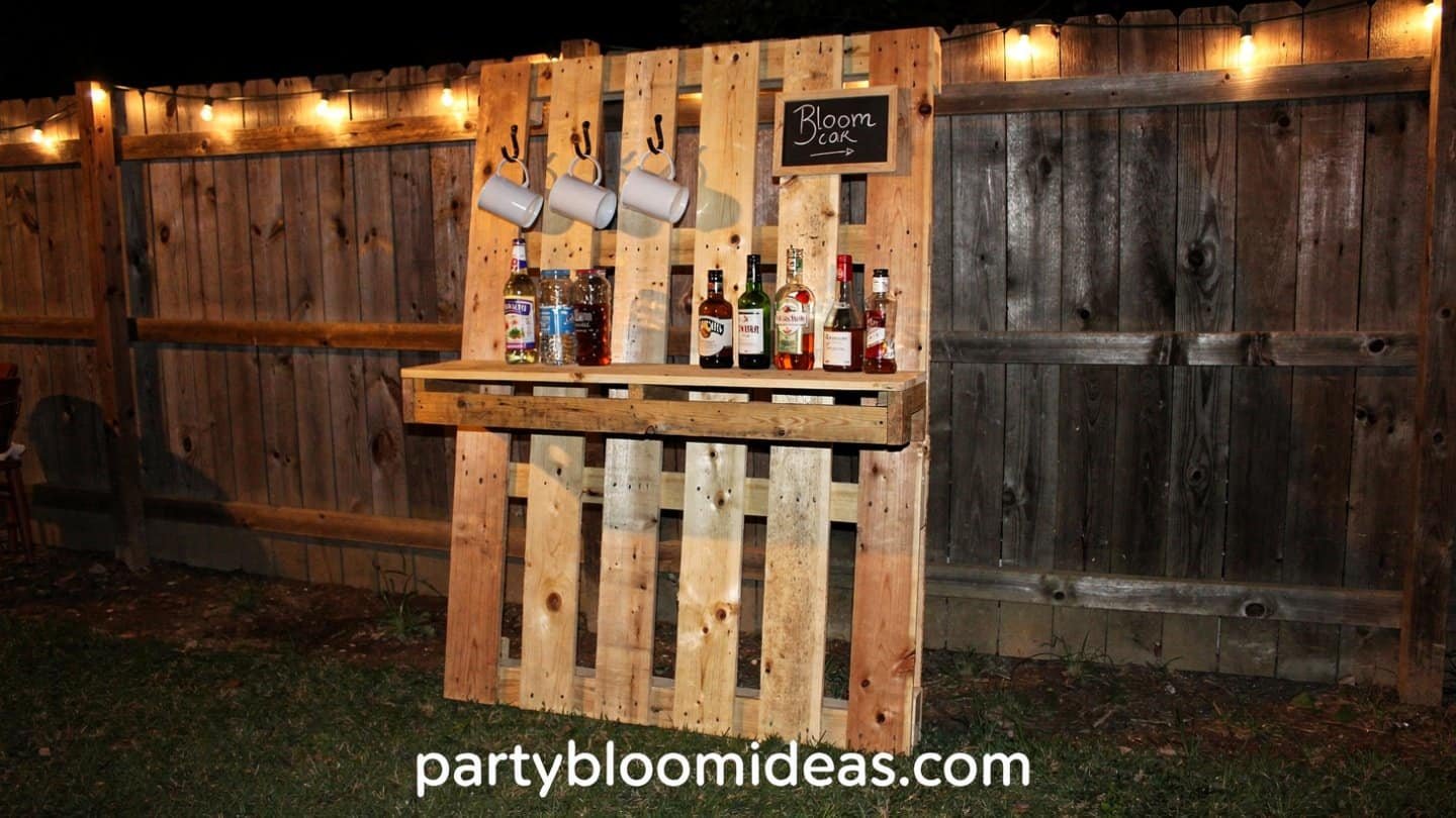 Rustic wooden pallet bar with bottles and string lighting at an outdoor party